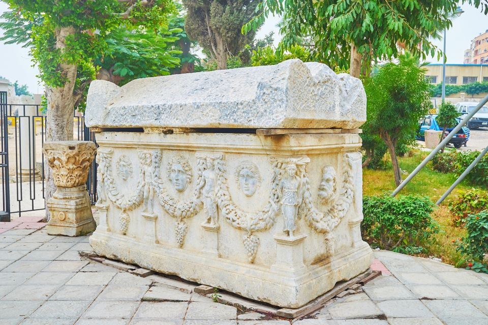 Ancient carved sarcophagus with bas-reliefs in an outdoor setting.