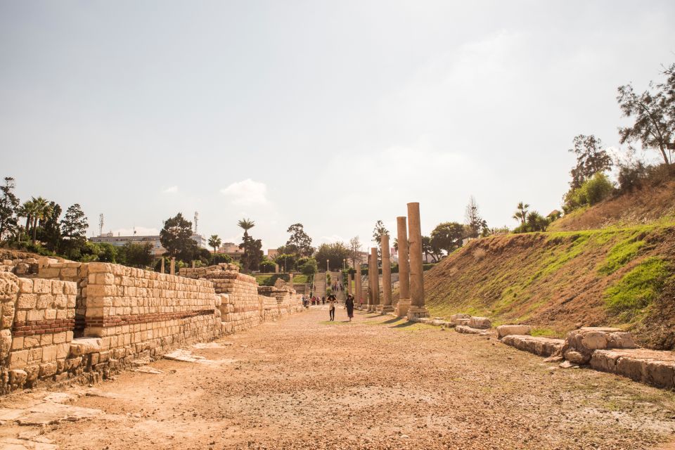 Ancient ruins with columns and visitors on a sunny day.