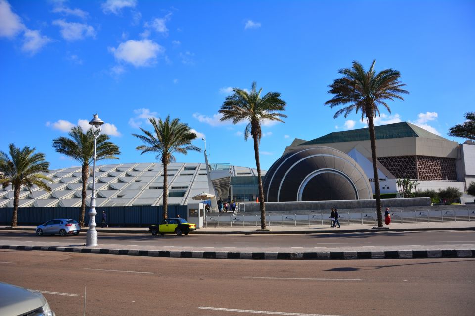 Modern building with dome and palm trees under blue sky.