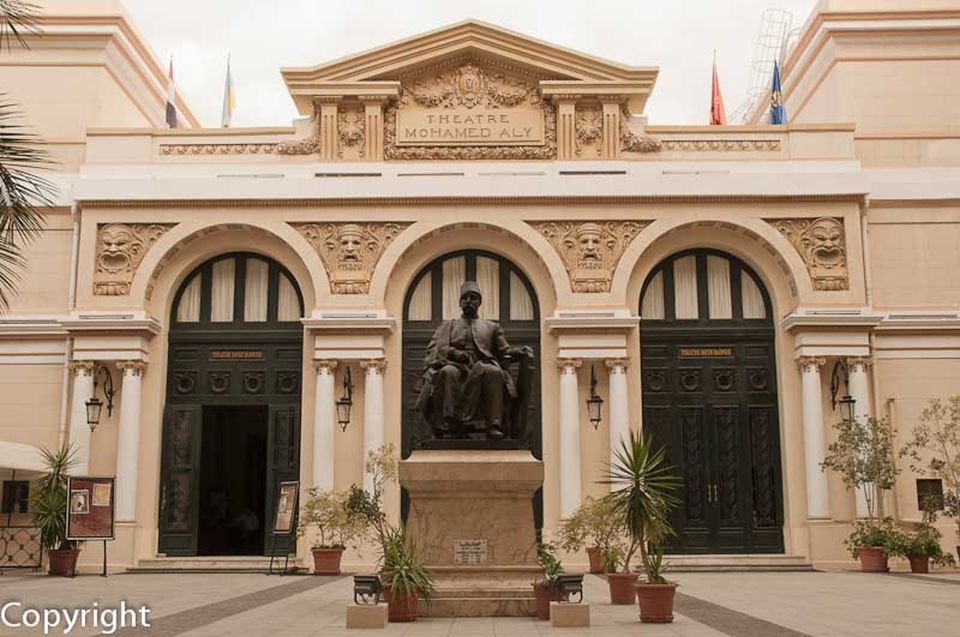 Statue in front of the "Theatre Mohamed Aly" with ornate architecture and potted plants.