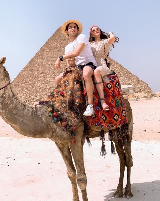 Couple riding a camel in front of the pyramids in cairo, Egypt