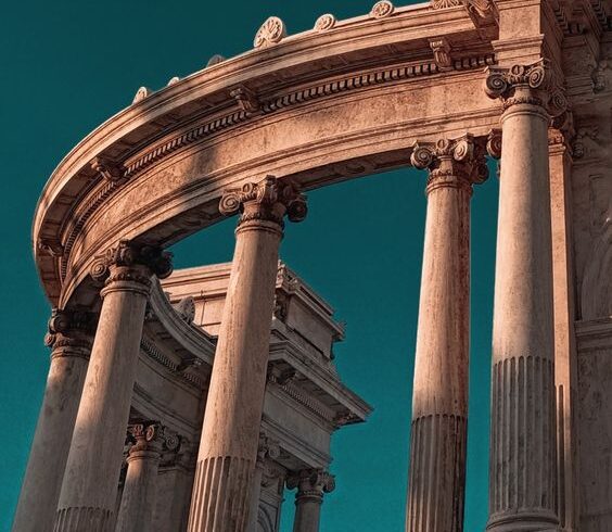 Majestic ancient stone pillars and arches against a clear blue sky, showcasing classical architecture.