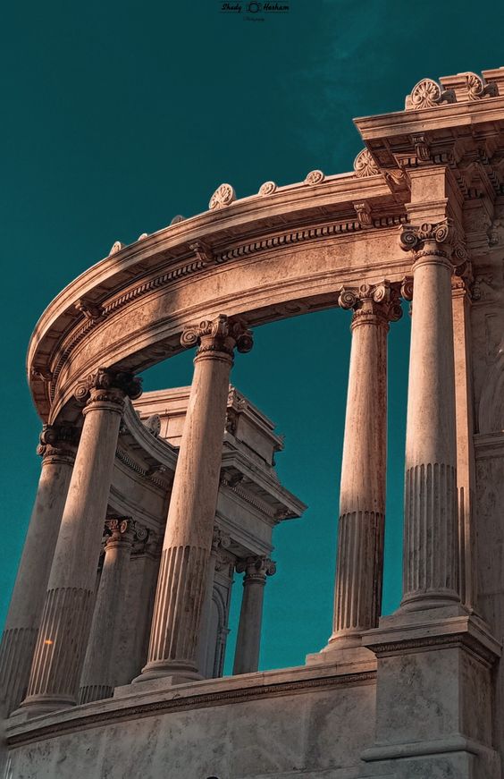 Majestic ancient stone pillars and arches against a clear blue sky, showcasing classical architecture.