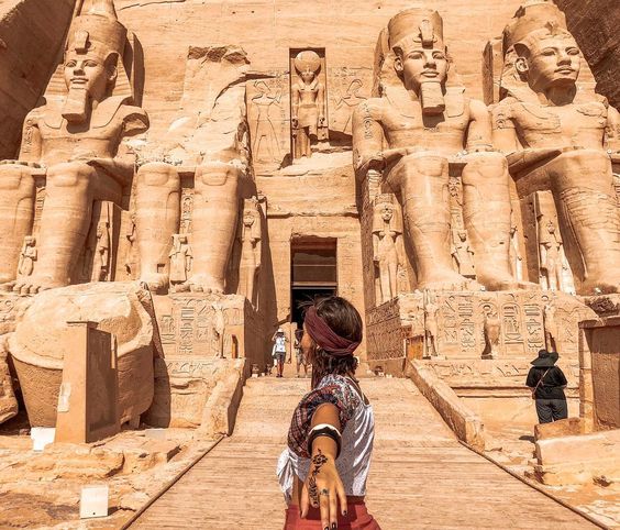 Person holding another's hand, leading towards the entrance of the Great Temple of Ramses II in Abu Simbel.