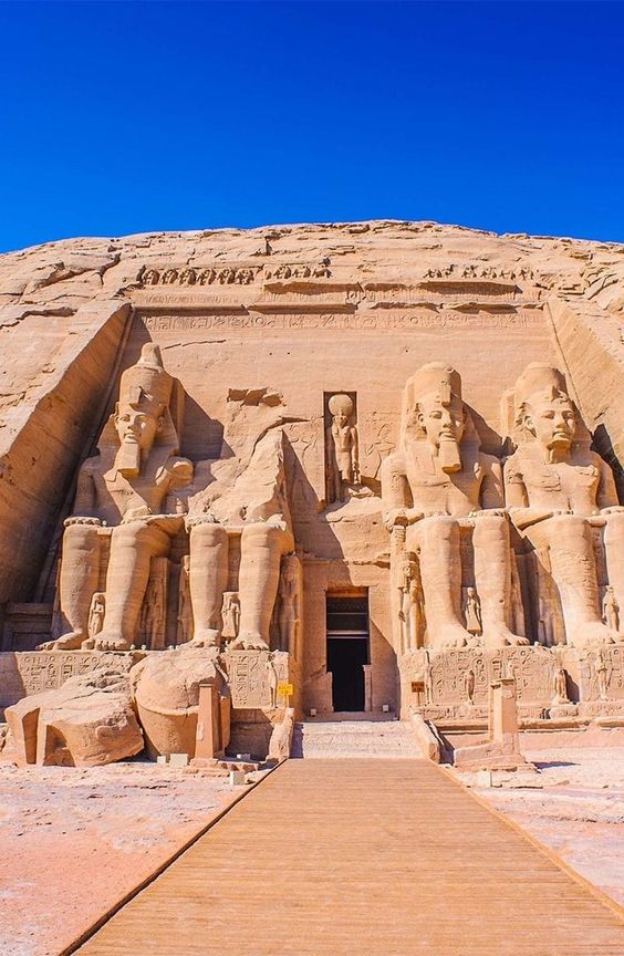 Ancient Egyptian temple facade with large statues and hieroglyphs.